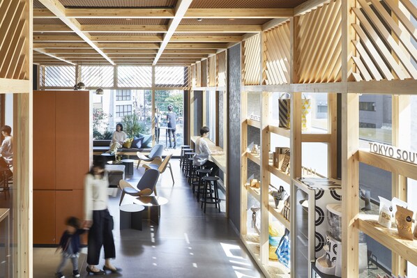 Un interior moderno con vigas de madera, zonas de estar y vistas a la calle.