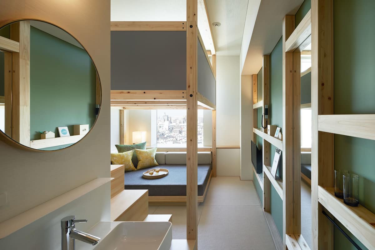 Une salle de bain moderne avec un grand miroir, un lavabo et un coin fenêtre agrémenté de coussins.