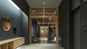 Un couloir moderne avec un banc en bois, un comptoir d’accueil et un plafond doté d’une structure en treillis de bois.