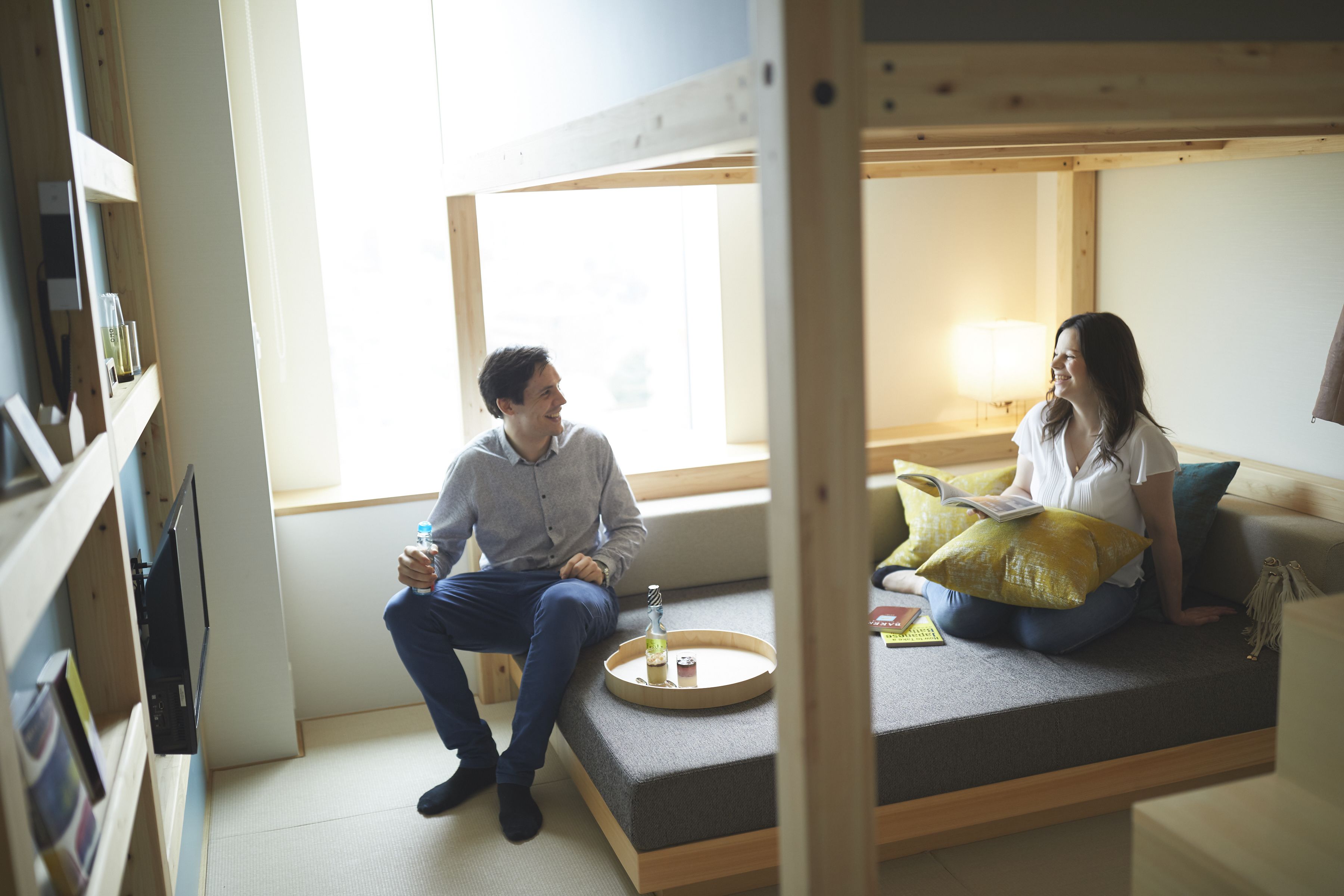 A cozy room with a built-in bench, a small table with a drink, and a window providing natural light.