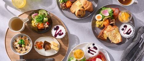 Diversos platos de desayuno como tostadas, huevos y ensaladas sobre una bandeja de madera.