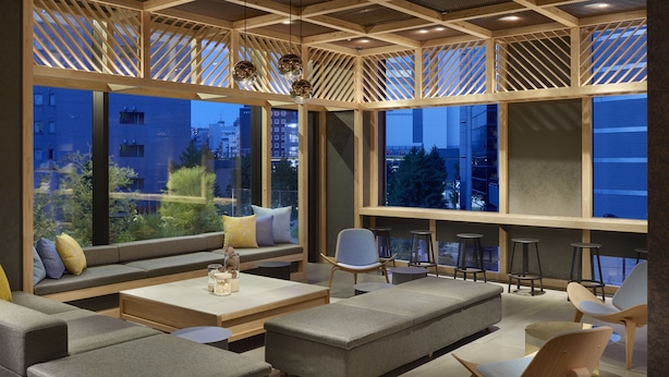 Un espace de détente moderne, doté de différents types de sièges, de grandes fenêtres et offrant une vue sur le paysage urbain.