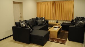 Una sala de estar moderna con un sofá modular, una mesa de centro y una ventana con cortinas.