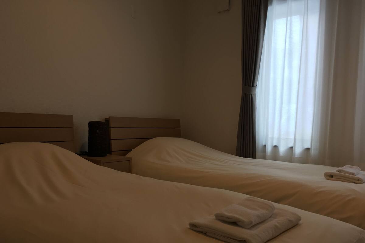 A hotel room with two beds, a nightstand, and a lamp.