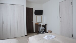 Un dormitorio con cama, un escritorio con silla, televisor y dos armarios.