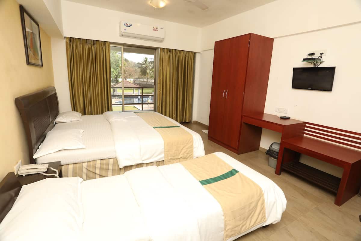 A hotel room with two beds, a desk, a TV, and a wardrobe.