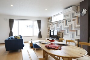 Un salón moderno con un sofá azul, una mesa de comedor de madera y una pared con estampado.