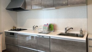 A modern kitchen with grey cabinets, a stainless steel sink, and a built-in dishwasher. - Jadan House (Furano)