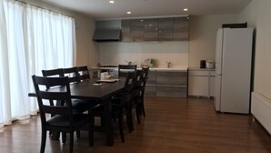 A modern kitchen with a dining table and chairs, a refrigerator, and a stove. - Jadan House (Furano)