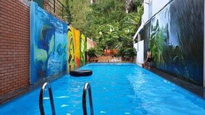 Una piscina con un mural en las paredes, una escalera y escalones que conducen a un nivel superior.