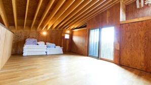 Ein Zimmer mit Holzbalken an der Decke, einem Stapel Handtücher und einem großen Fenster.