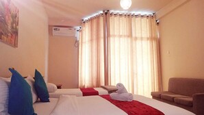 A hotel room with two beds, a red blanket, a white towel, a ceiling fan, and a large window with curtains. - Ella Mansion (Ella)