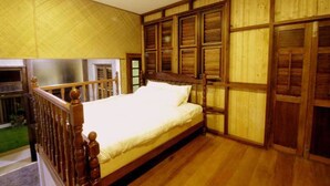 Une chambre avec un lit en bois, une grande fenêtre et un panneau mural en bois.