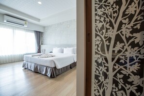 A hotel room with a neatly made bed, a large window with curtains, and a wall with a floral pattern. - Juntra Resort and Hotel (Nakhon Nayok)