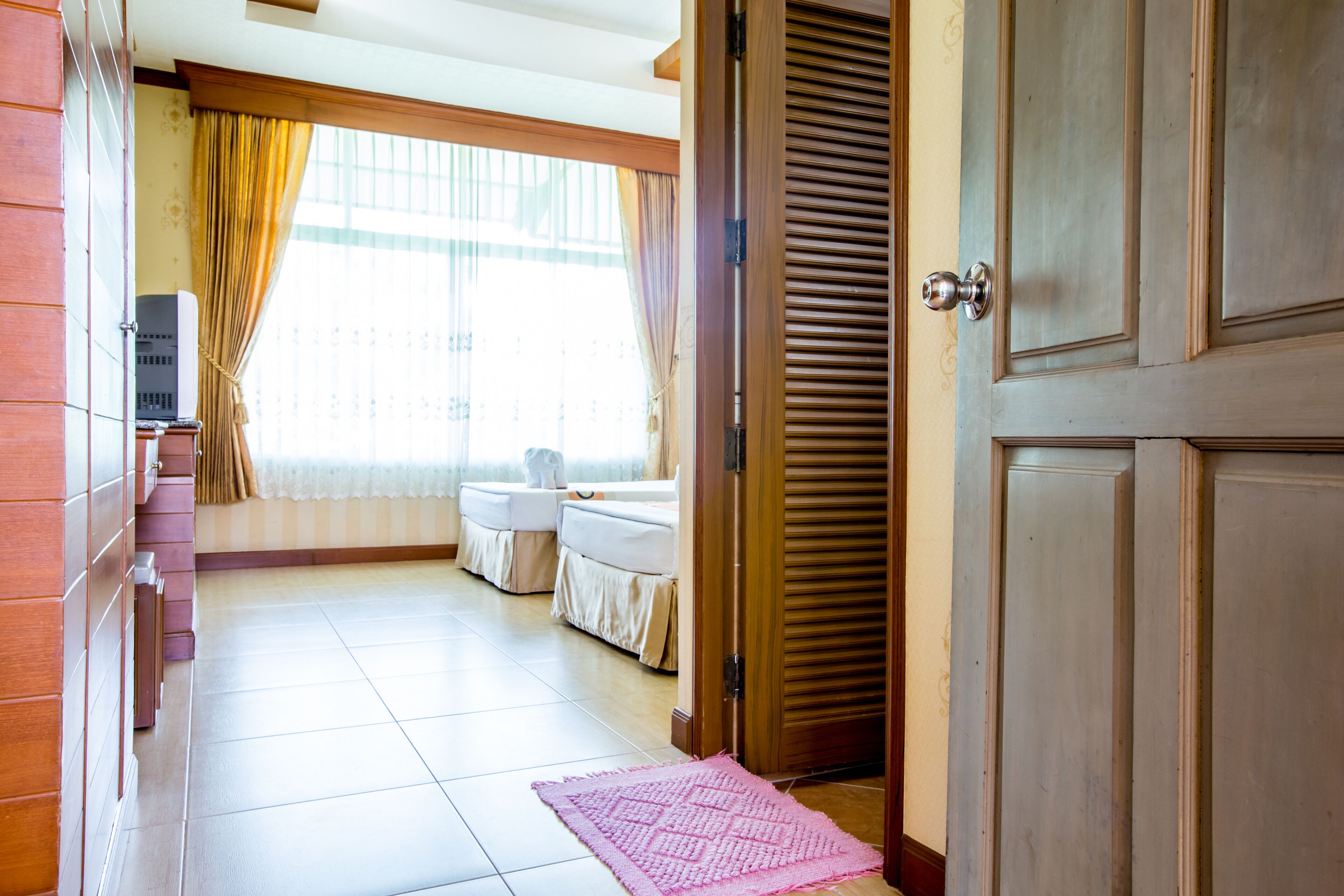 Una habitación de hotel con cama, escritorio y ventana con cortinas.