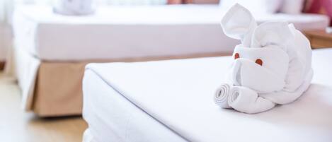 A neatly made white towel on a bed with a white pillow and a small white object on the bed.