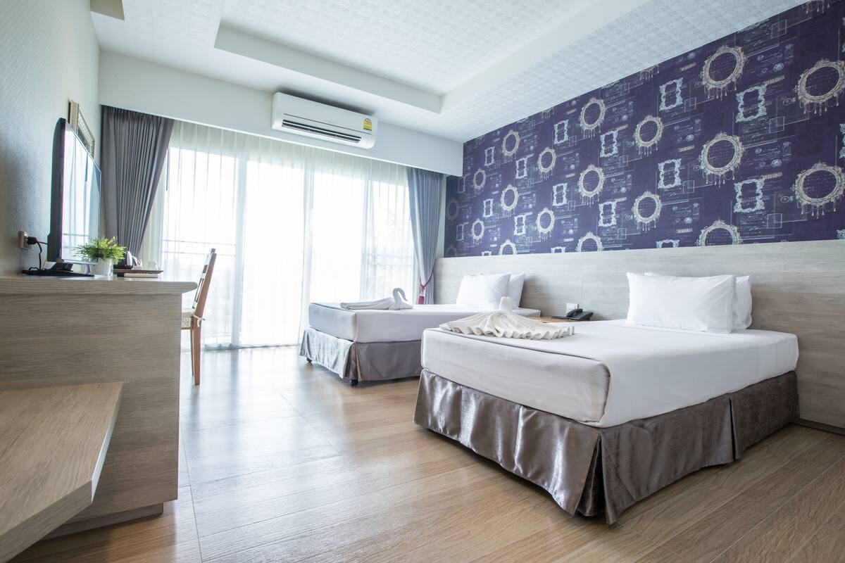 A hotel room with a large bed, a desk, a chair, and a view of the outdoors.