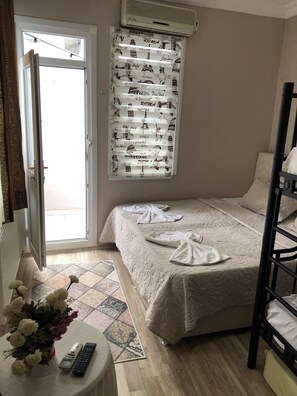 A bedroom with a bed, a window with a curtain featuring city landmarks, a bedside table with a remote control, and a flower vase. - Avrasya Hostel (Istanbul)