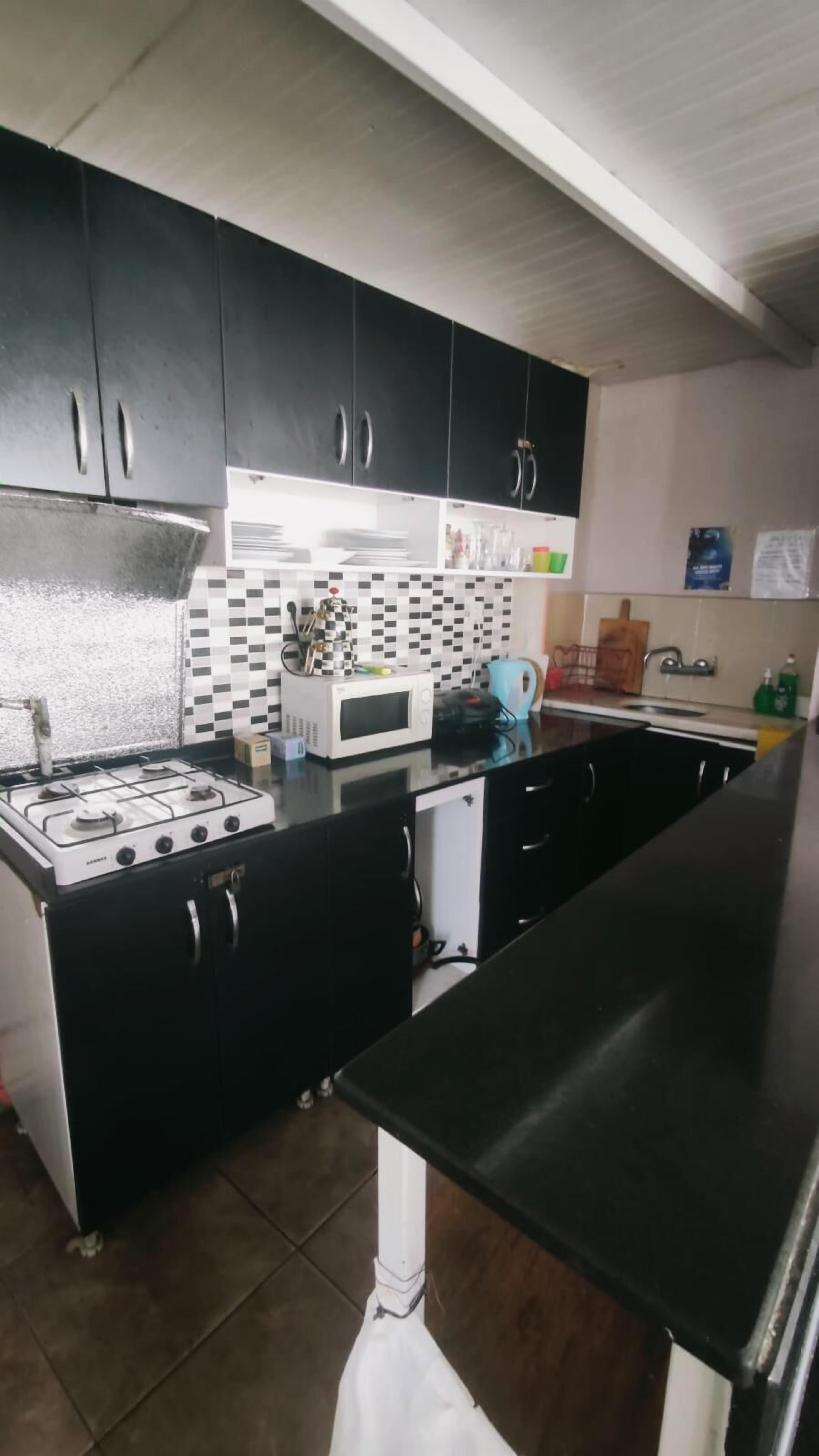 A kitchen with black cabinets, a gas stove, a microwave, and a tiled backsplash.