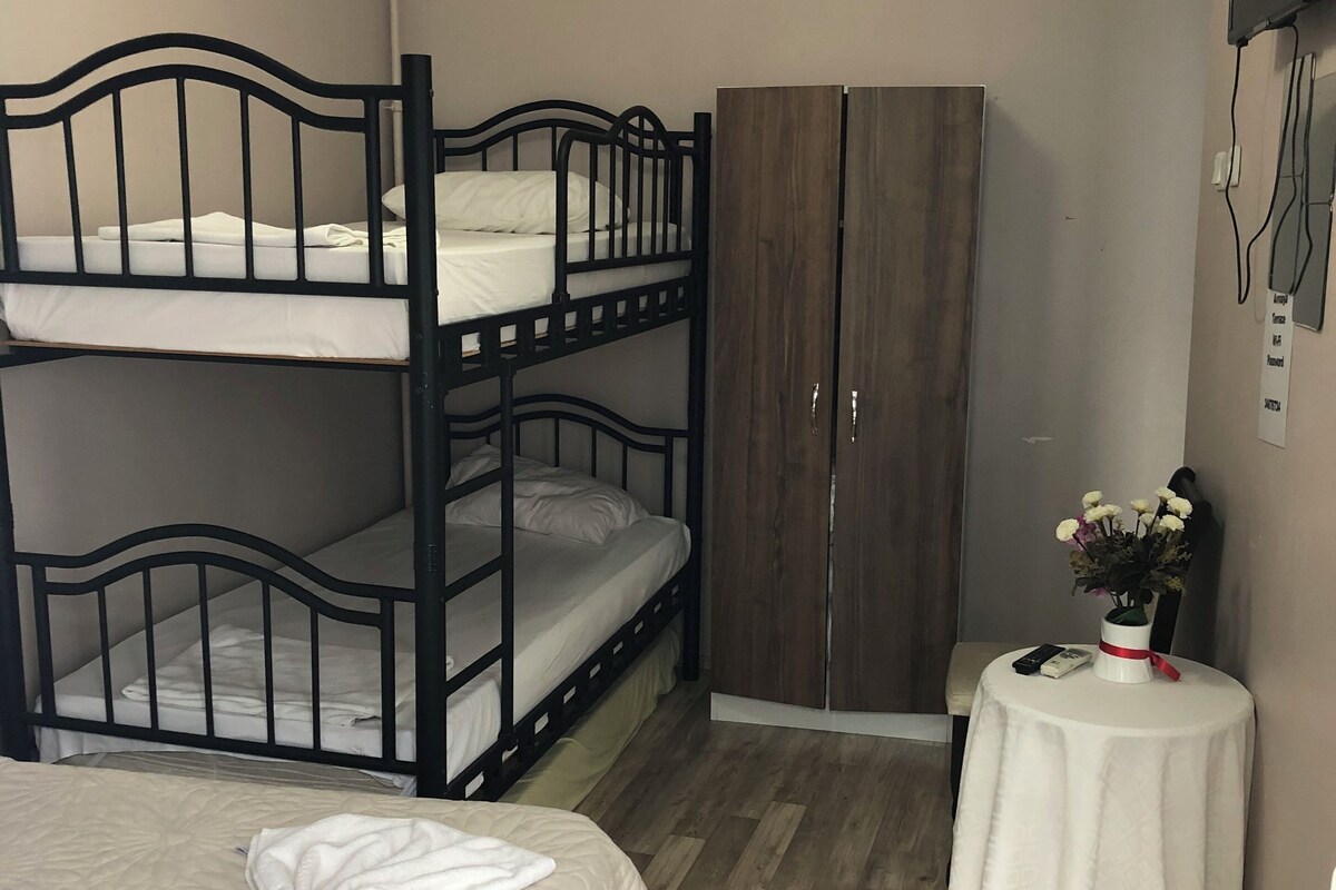 A room with bunk beds, a wardrobe, a small table with a vase, and a patterned rug.
