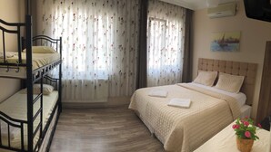 Un dormitorio con una cama litera, una cama individual y una ventana con cortinas florales.
