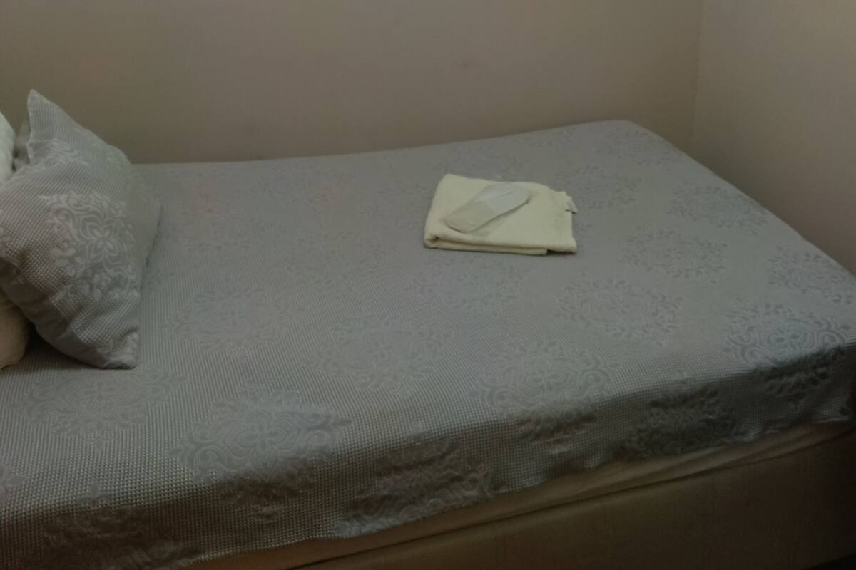 A single bed with a white mattress and a folded white blanket.