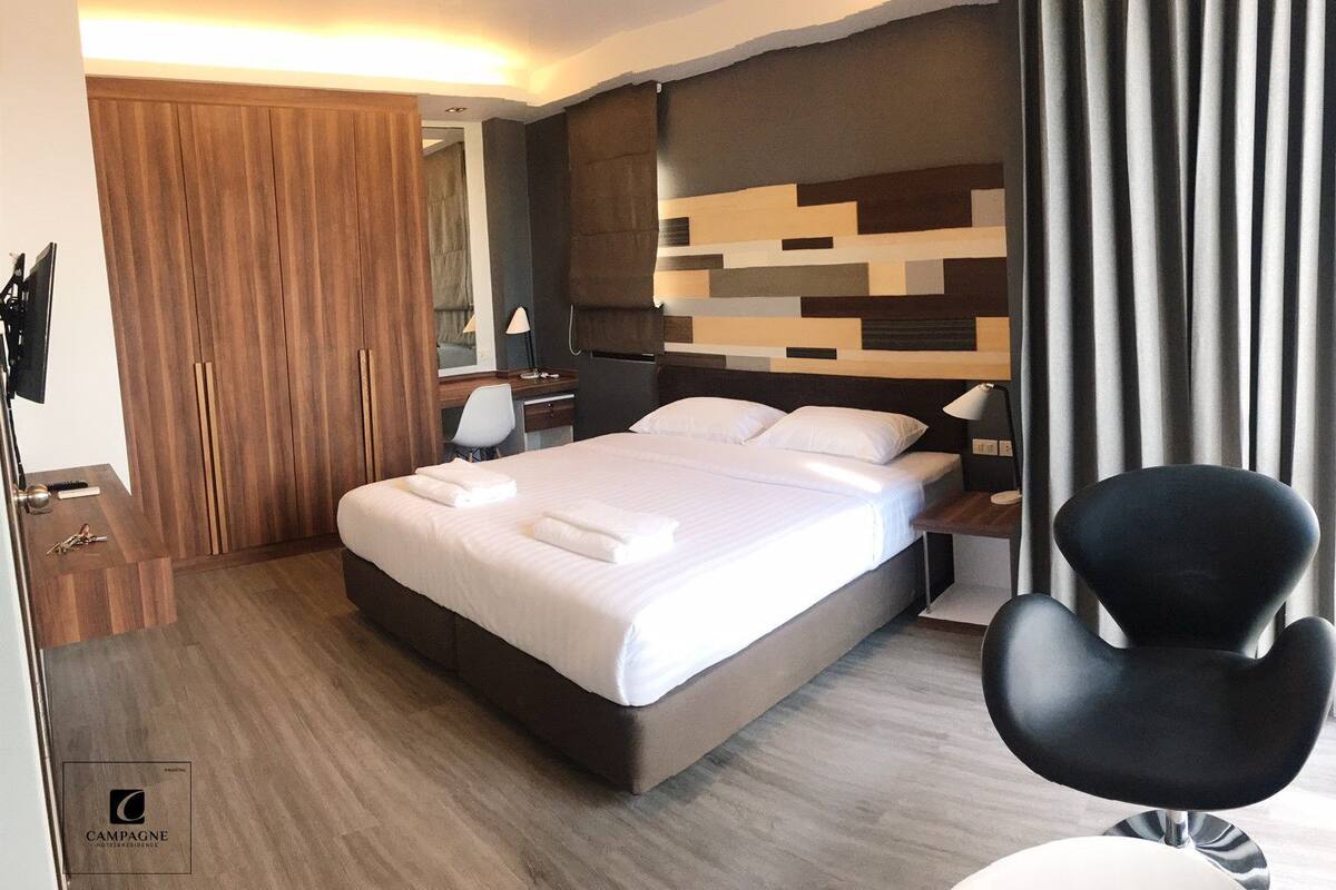 Une chambre d’hôtel moderne équipée d’un grand lit, d’un bureau, d’une chaise et d’une armoire.