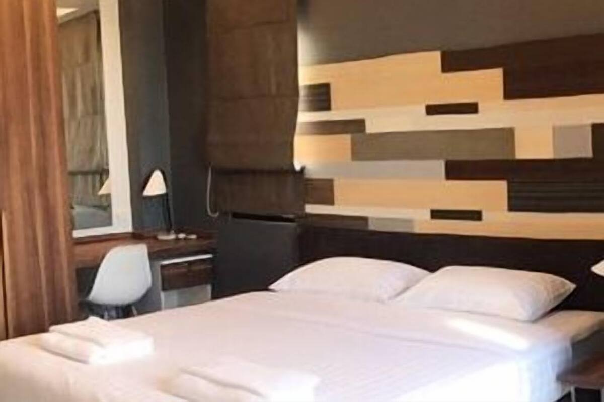 Une chambre d’hôtel avec un lit, un bureau, une chaise et un miroir.