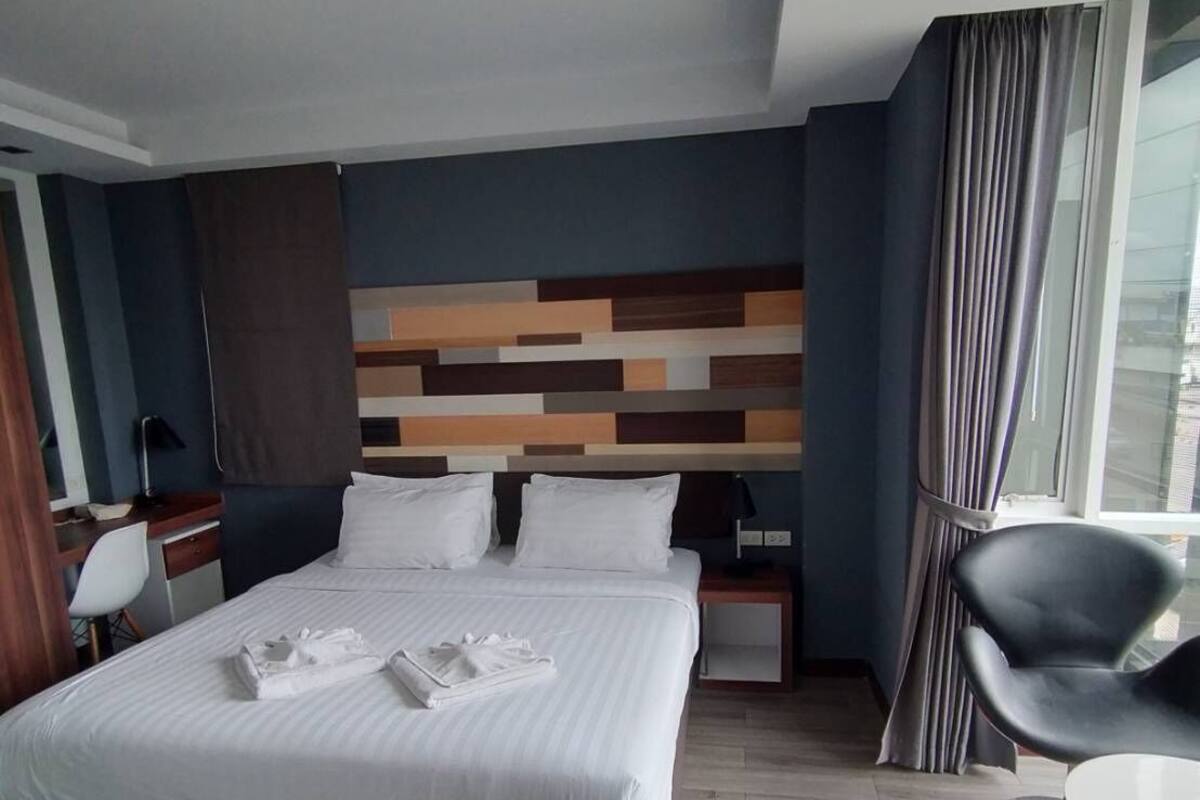 Une chambre d’hôtel avec un grand lit, un bureau, une chaise et une petite table.