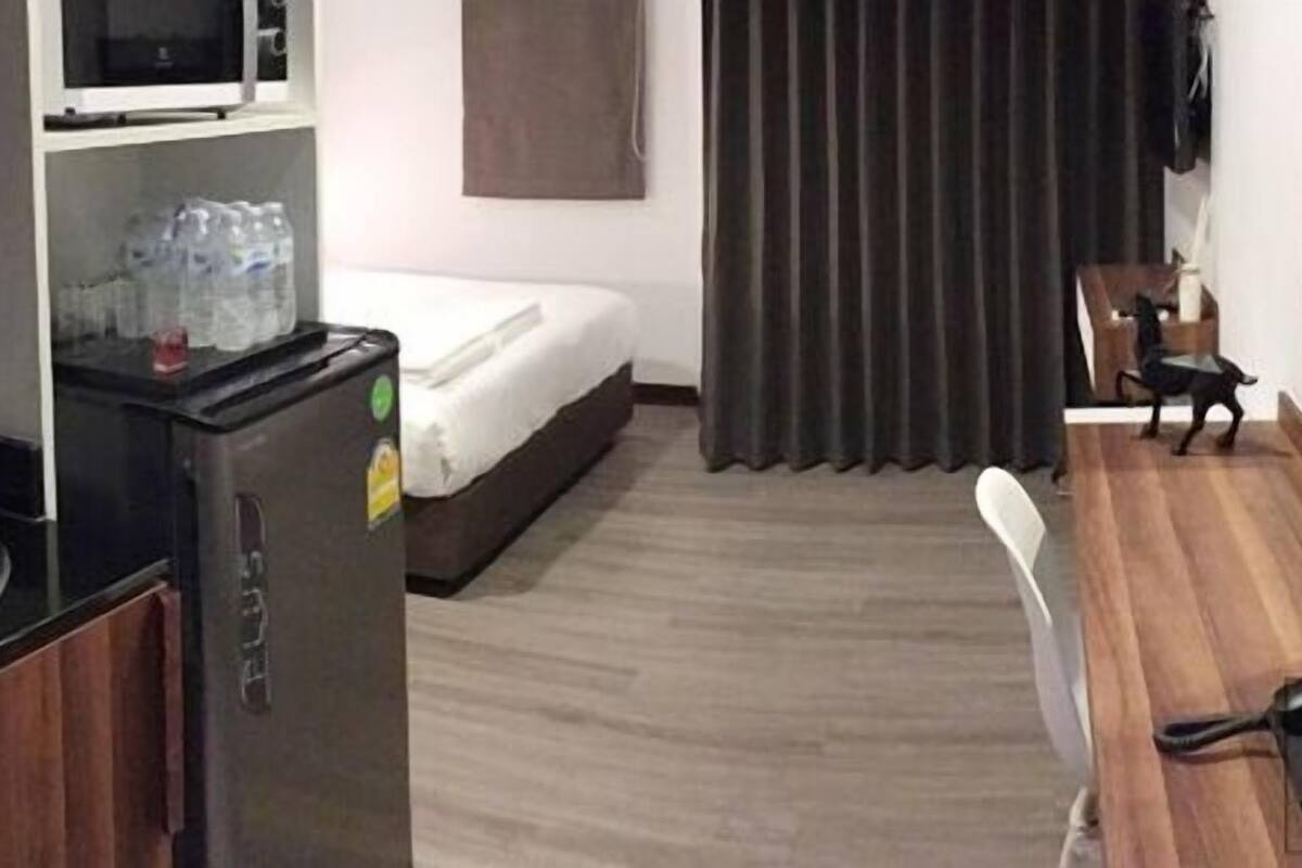 Une chambre d’hôtel compacte comprenant un coin cuisine, un lit, un espace repas et une fenêtre recouverte d’un rideau.