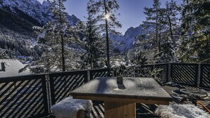 Un tavolo di legno con un bicchiere, sullo sfondo di una montagna innevata.