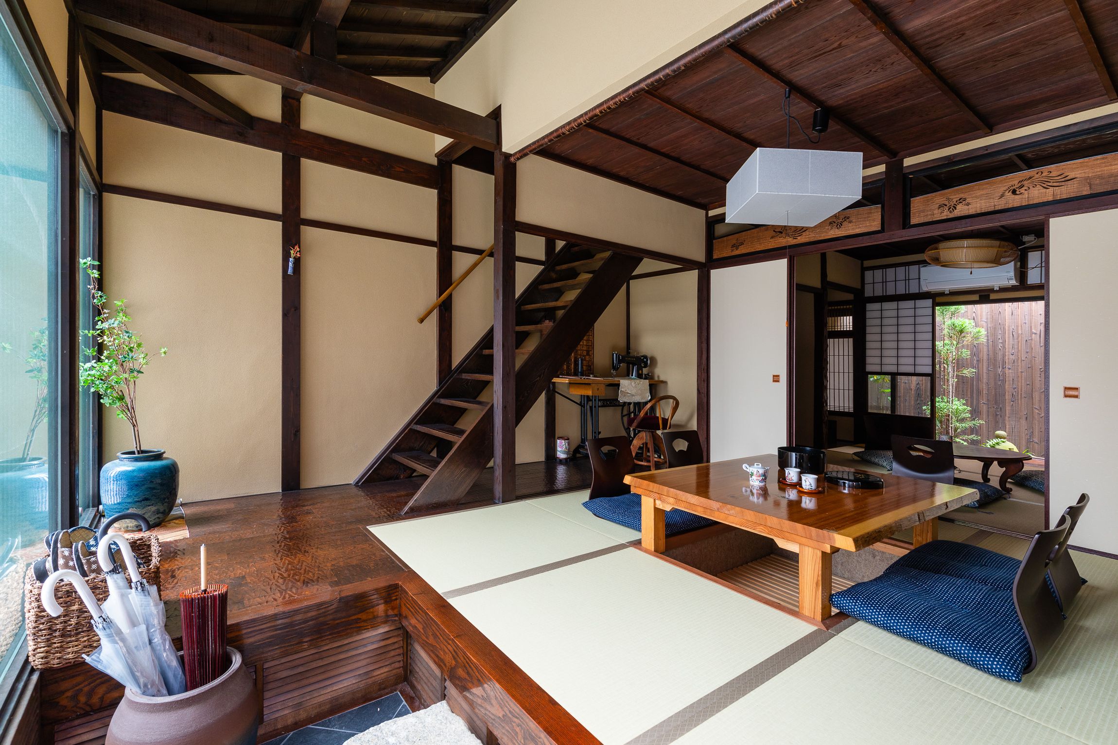 Ein traditioneller japanischer Raum mit Tatami-Böden, einem Holztisch und einer Treppe.