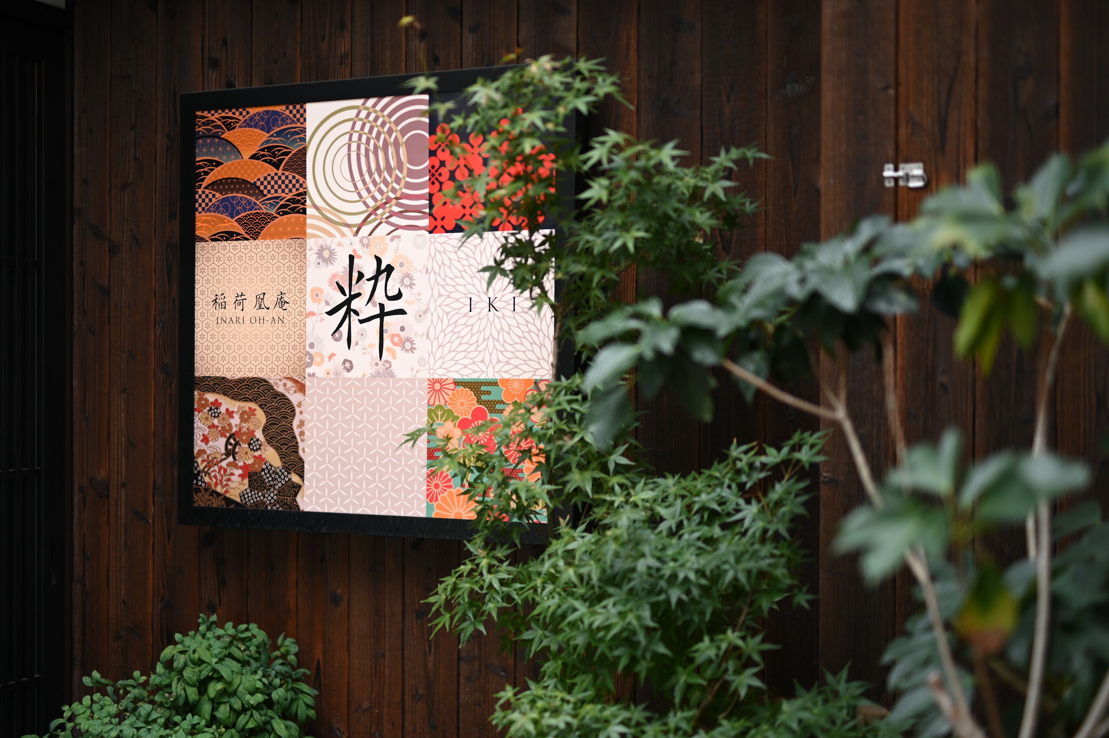 A framed artwork with various patterns and text on a wooden wall.
