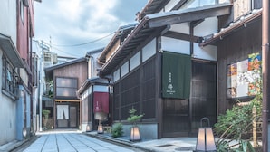 A narrow street with traditional Japanese architecture, including wooden buildings and a small shop with a green sign. - Inari Ohan (Kyoto)