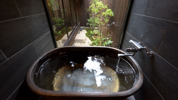 A modern bathroom with a freestanding bathtub, a window, and a small garden view. - Inari Ohan (Kyoto)