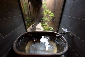 A modern bathroom with a freestanding bathtub, a window, and a small garden view. - Inari Ohan (Kyoto)