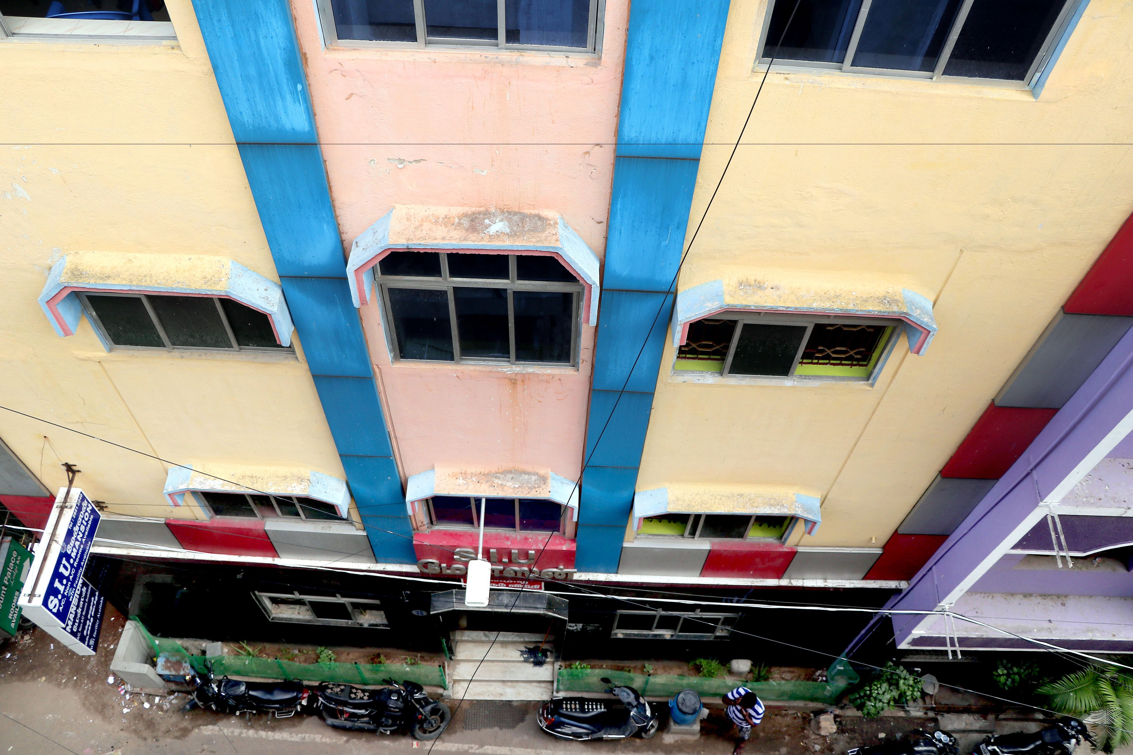 A multi-story building with a central staircase, multiple windows, and a signboard.