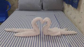 A bed with striped bedding and a heart-shaped towel arrangement.