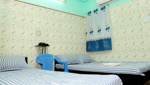 Una habitación con dos camas, una silla azul, un teléfono y un aire acondicionado.