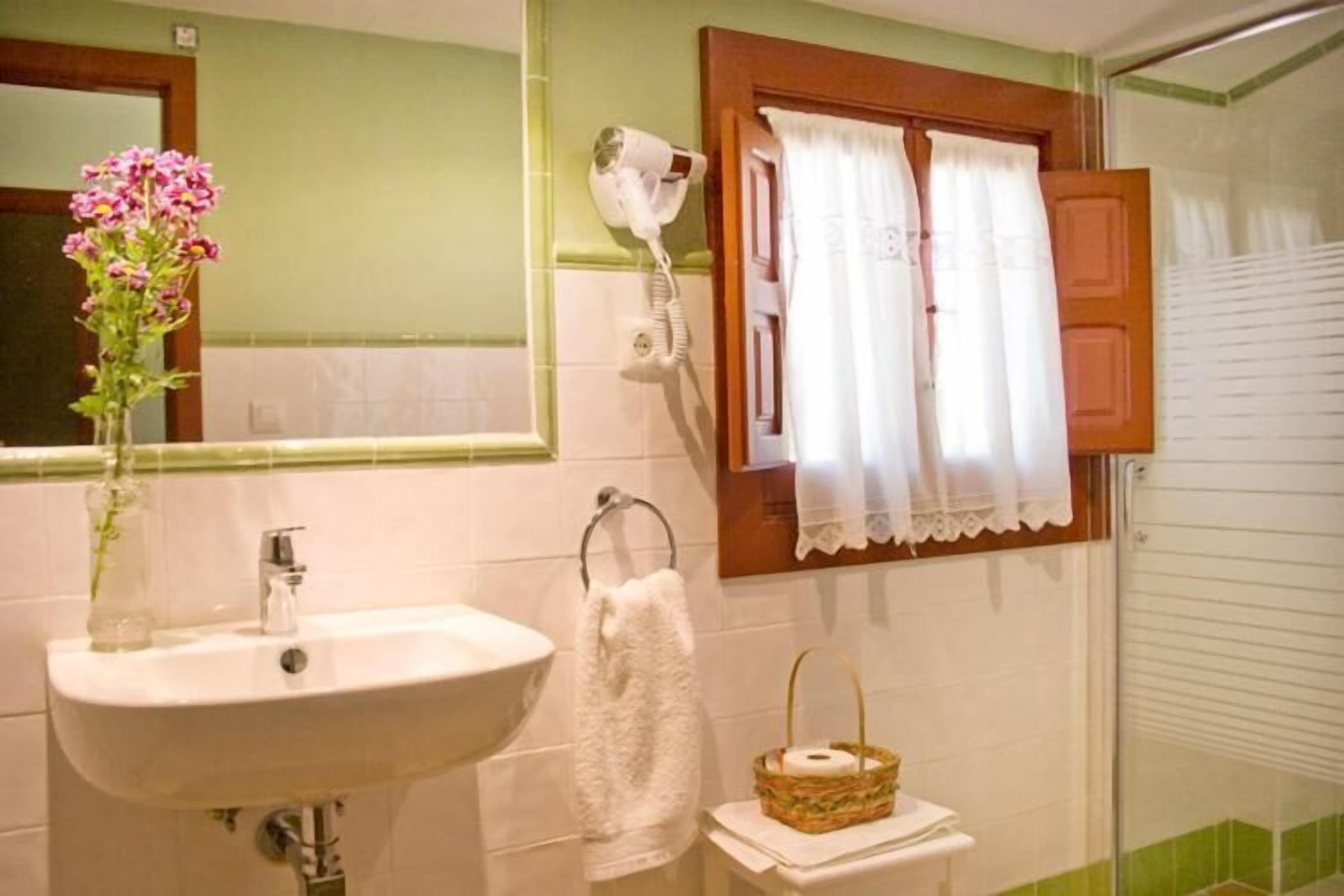 Een badkamer met een wastafel, een haardroger, een spiegel, een handdoek en een mand.
