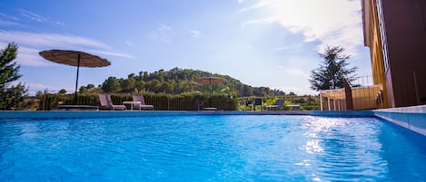 Una piscina al aire libre de temporada, sillones reclinables de piscina