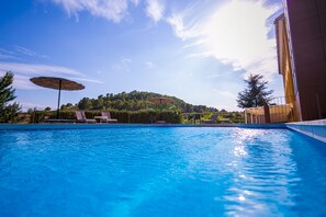 Una piscina al aire libre de temporada, sillones reclinables de piscina
