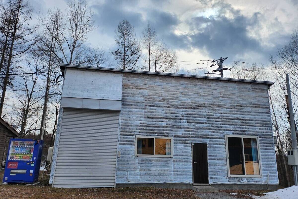 A small, single-story building with a garage door, a small window, and a door.