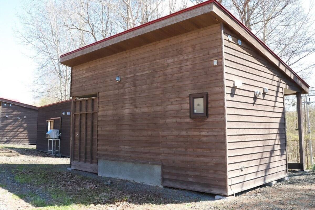 A small wooden cabin with a red roof, a door, and a small window.