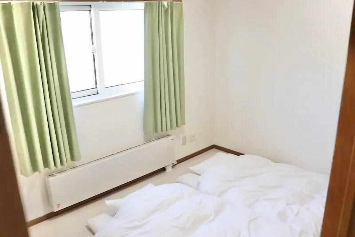 A room with a bed, a window with curtains, and a radiator.