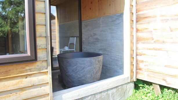 A wooden cabin with a large stone planter in the entrance area. - Auberge Ninguruforet (Biei)