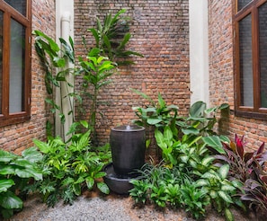A courtyard with a brick wall, a water feature, and various plants. - Treasures Hotel and Suites (Malacca City)