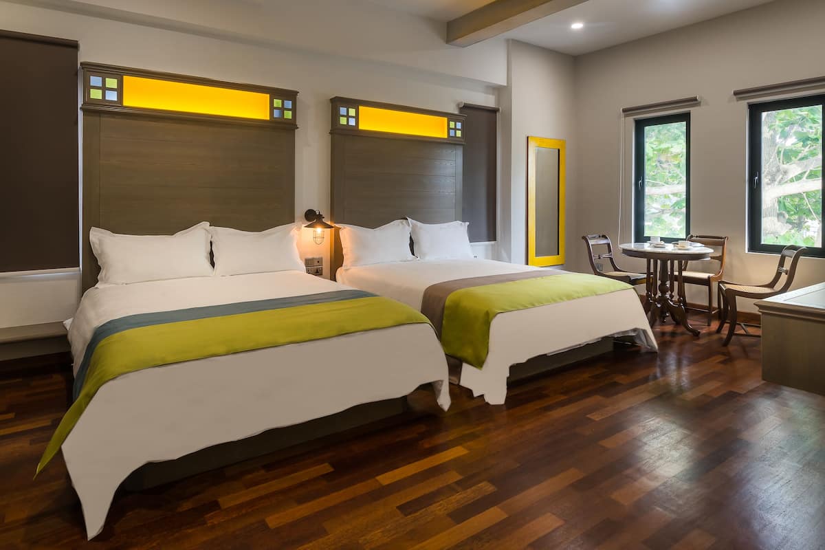 Ein Hotelzimmer mit zwei Betten, einem kleinen Tisch und einem Stuhl.