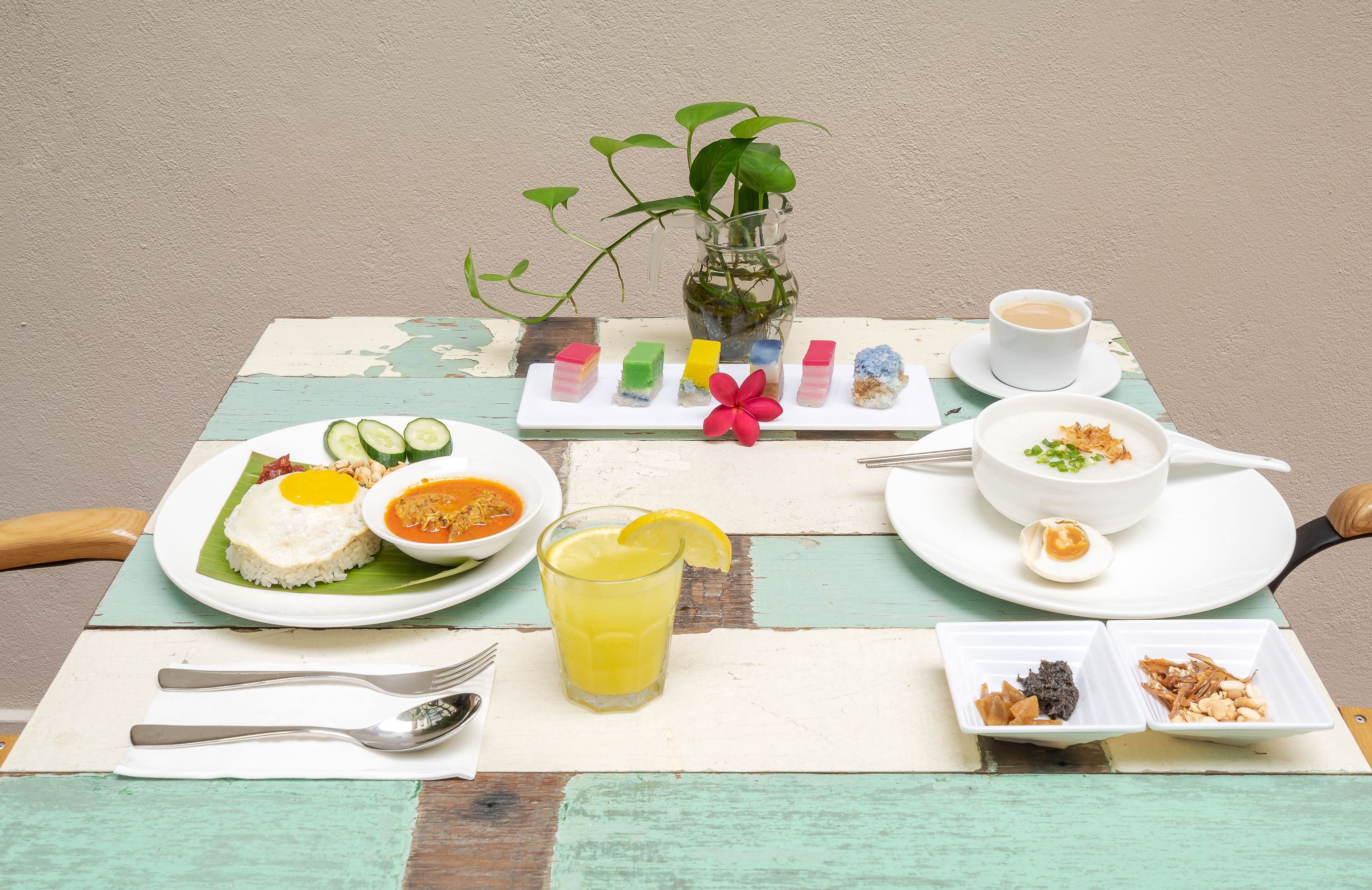 A table set with a variety of dishes including rice, soup, and a fruit salad, along with a cup of coffee and a glass of juice.