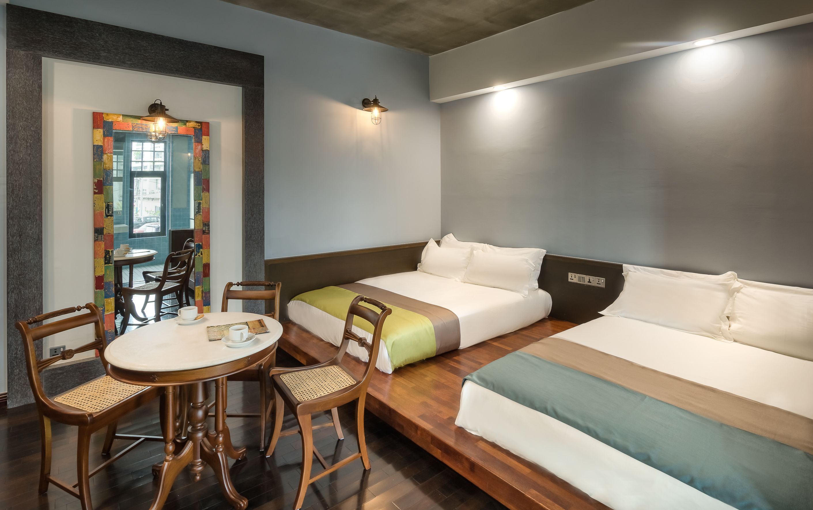 A hotel room with a bed, a small table with chairs, and a colorful wall decoration.